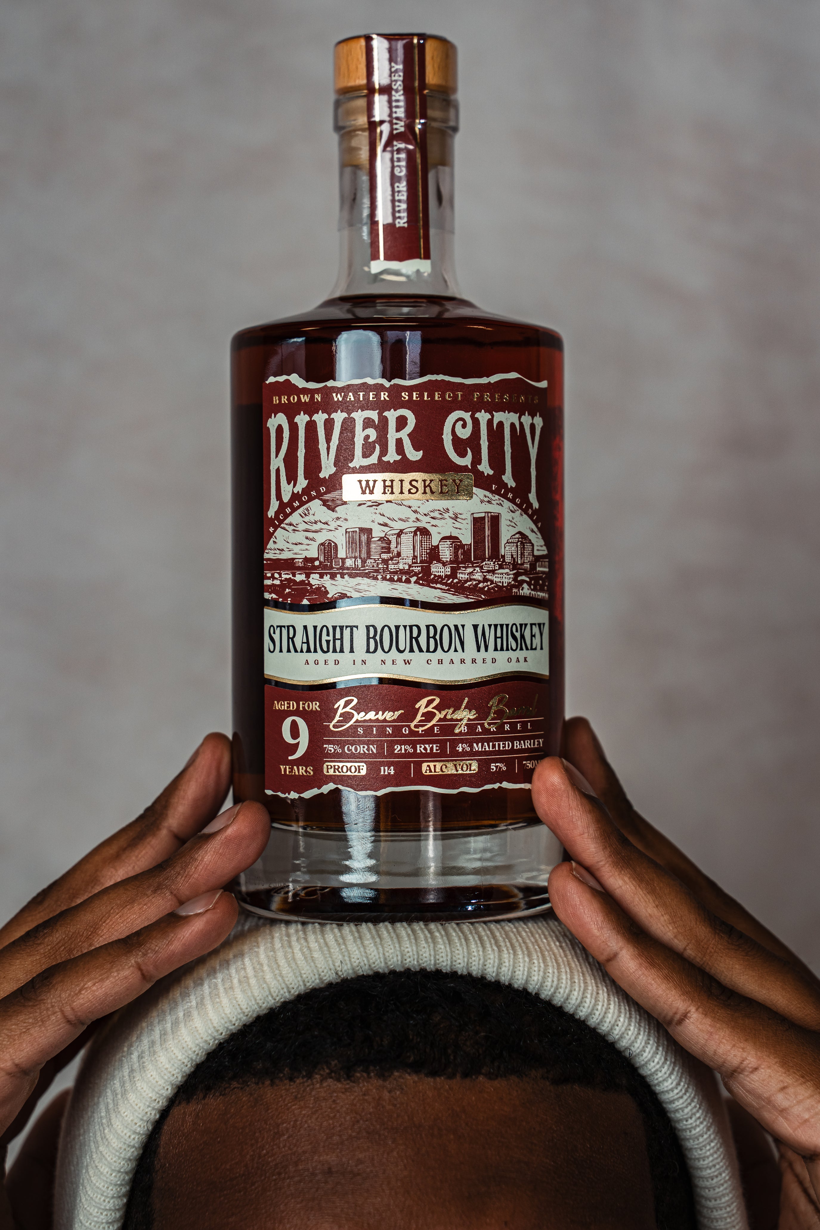 Bottle of River City Whiskey Balanced on a Head Styled with a Knit Cap